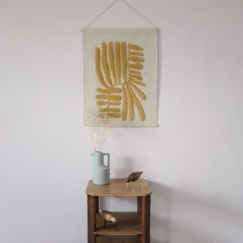 Wandkleed Minerva in okergeel en beige met bladmotief – bohemien muurdecoratie van wol.