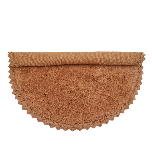 Het ronde toffeekleurige katoenen vloerkleed Perla, stijlvol voor de helft opgerold op een witte achtergrond.