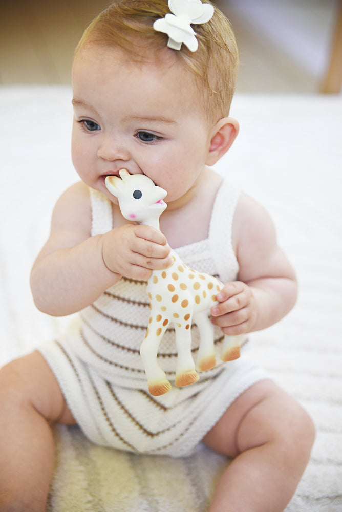 Een baby die veilig bijt op de poten van Sophie de giraf voor verlichting bij doorkomende tandjes.
