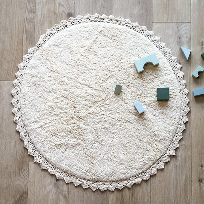Sfeerafbeelding van het ronde ecru vloerkleed Perla in een kinderkamer met houten bouwblokken als speelkleed.