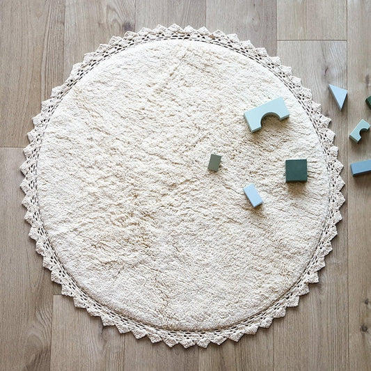 Sfeerafbeelding van het ronde ecru vloerkleed Perla in een kinderkamer met houten bouwblokken als speelkleed.