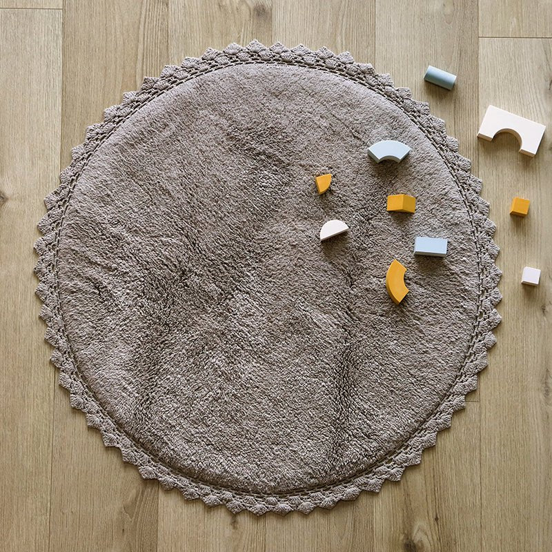 Sfeerafbeelding van het ronde grijze vloerkleed Perla in een kinderkamer met houten bouwblokken als speelkleed.