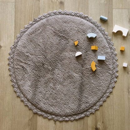Sfeerafbeelding van het ronde grijze vloerkleed Perla in een kinderkamer met houten bouwblokken als speelkleed.