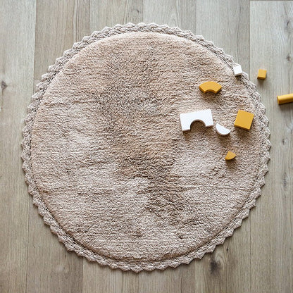 Sfeerafbeelding van het ronde nude roze vloerkleed Perla in een interieur met houten bouwblokken als speelkleed.