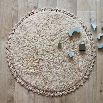 Sfeerafbeelding van het ronde zandbeige vloerkleed Perla in een kinderkamer met houten bouwblokken als veilig speelkleed.
