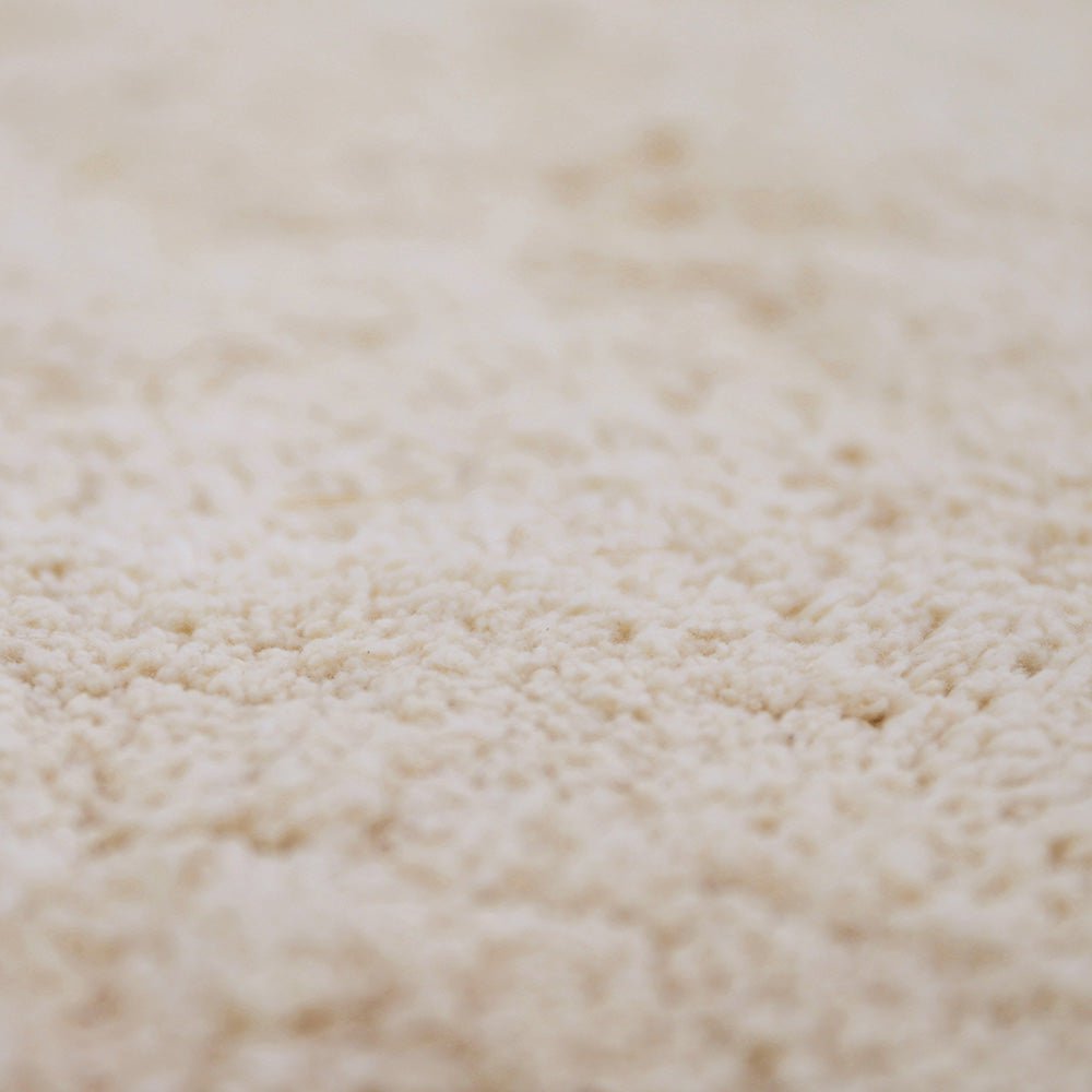 Close-up van de zachte, handgetufte katoenen bovenkant van het Perla vloerkleed in de kleur sable zandbeige.
