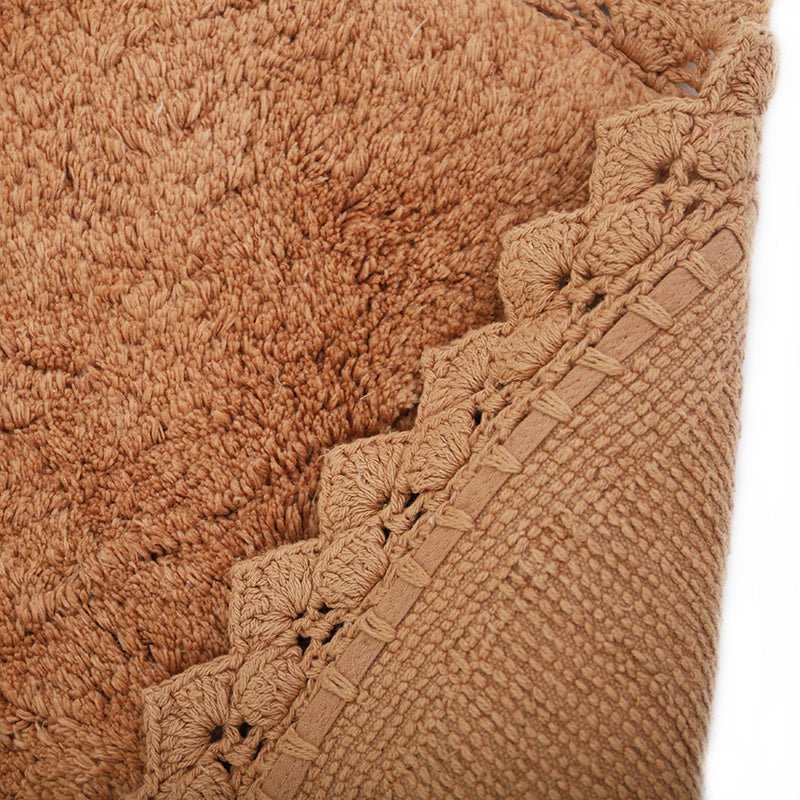 Close-up detail van de textuur en de omgeslagen achterkant van het handgetufte katoenen Perla vloerkleed in de kleur toffee.