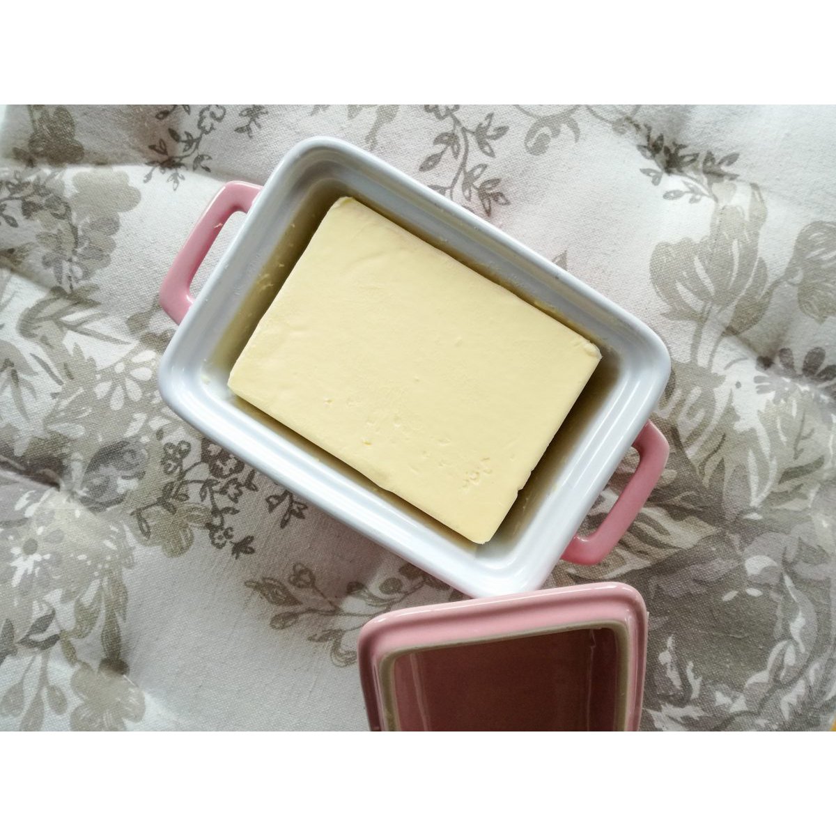 Bovenaanzicht van de roze keramische botervloot (16,5 cm) gevuld met een pakje boter