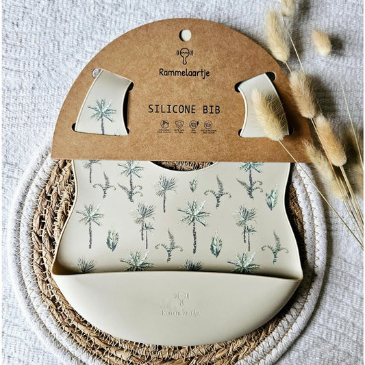 Beige siliconen slabber met jungle plantenprint en palmbladeren voor baby en peuter tijdens het eten