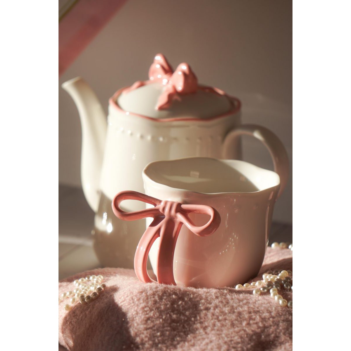 Sfeerimpressie van de Ribbon Grace theeset met de roze lint mok op de voorgrond en de theepot op de achtergrond.