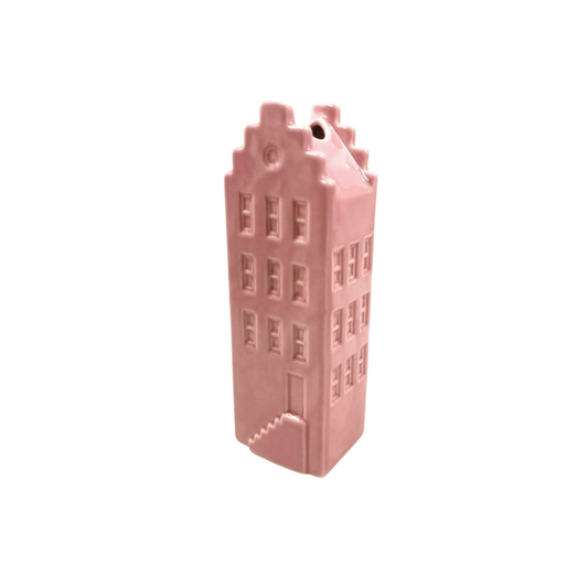 Roze keramieken vaas in de vorm van een Amsterdams herenhuis tegen een witte achtergrond.